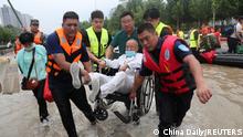 Rescue workers transfer a patient in a wheelchair at the Fuwai Central China Cardiovascular Hospital which was flooded following heavy rainfalls in Zhengzhou, Henan province, China July 22, 2021. China Daily via REUTERS ATTENTION EDITORS - THIS IMAGE WAS PROVIDED BY A THIRD PARTY. CHINA OUT.
