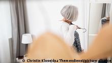 ILLUSTRATION - Eine aeltere Frau steht am 03.04.2018 in einer Wohnung in Hamburg vor einem Spiegel und ueberlegt, was sie anziehen kann (gestellte Szene). Foto: Christin Klose || Modellfreigabe vorhanden