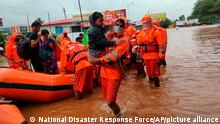 This photograph provided by India's National Disaster Response Force (NDRF) shows NDRF personnel rescuing residents in Chiplun area in the western Indian state of Maharashtra, Friday, July 23, 2021. Officials say landslides and flooding triggered by heavy monsoon rain have killed more than 100 people in western India. More than 1,000 people trapped by floodwaters have been rescued.(National Disaster Response Force via AP)