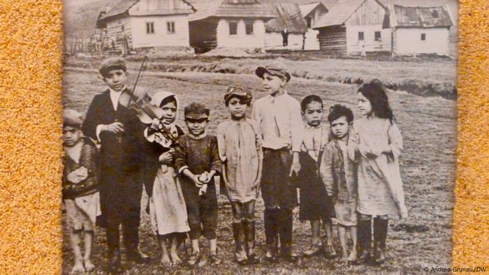 A black-and-white picture shows nine children, one of them with a violin