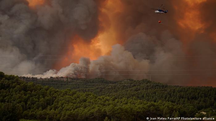 A firefighting plane is seen flying above wildfires in northeast Spain