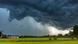 A massive, dark storm cloud moves over a green field in Bavaria A massive, dark storm cloud moves over a green field in Bavaria