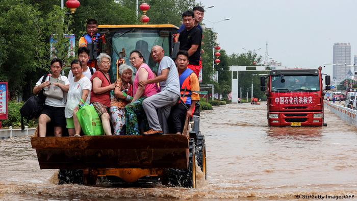 Ein Radlader transportiert gerettete Menschen in seiner Baggerschaufel durch eine überflutete Strasse in Weihui in der chinesischen Provinz Hunan. 