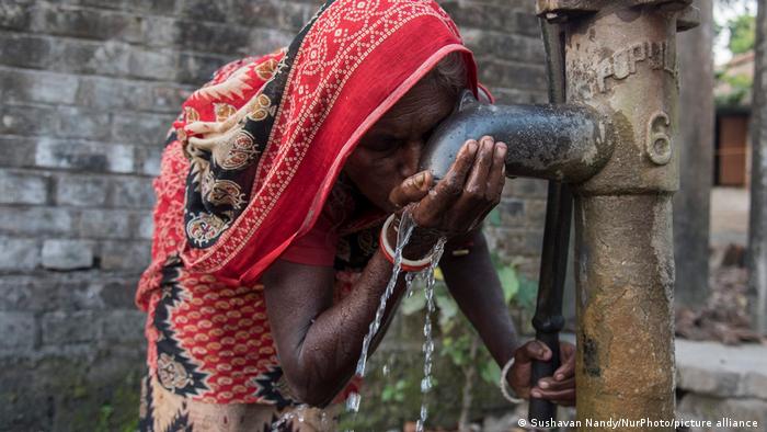 Woman drinking from a public tap in India