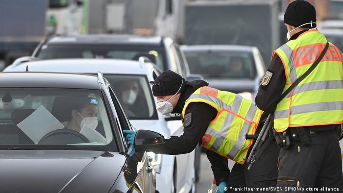 Police controlling drivers at the border, everyone wearing a face mask.