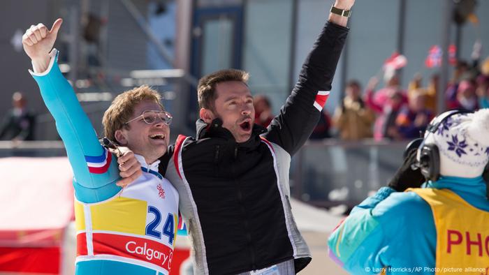 In one scene from the movie Eddie the Eagle, a ski jersey and its coach throw their arms in jubilation.