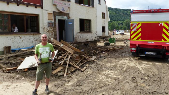 Benno Gilles entouré de débris et de boue devant sa maison