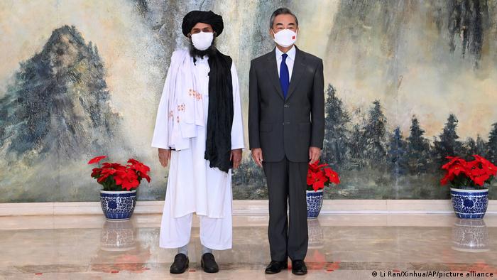 Taliban co-founder Abdul Ghani Baradar stands next to China's foreign minister Wang Yi
