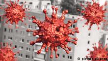 Mehrere Modelle eines Corona-Virus fliegen durch die Luft vor einem Häuserblock