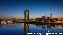 Die Europäische Zentralbank (EZB) und die Frankfurter Skyline spiegeln sich nach Sonnenuntergang im Main.