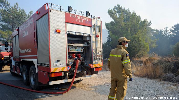 A Greek firefighter battles a forest fire on the island of Rhodes