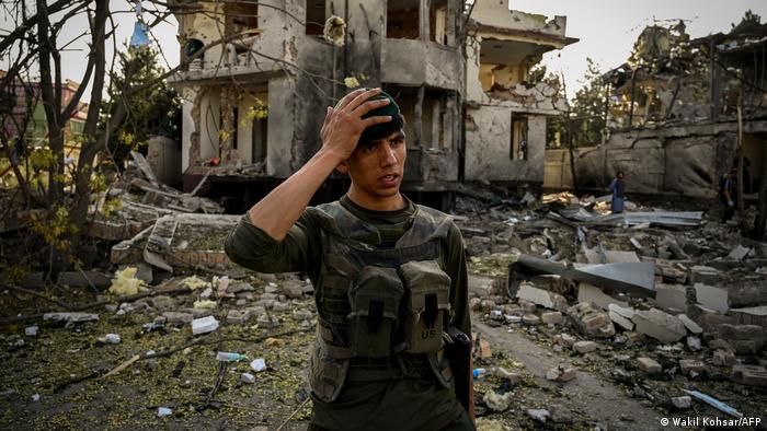 Militar fala, segurando a cabeça, em meio a destroços de prédios