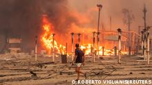 A man walks in front of a fire at Le Capannine beach in Catania, Sicily, Italy, July 30, 2021, in this photo obtained from social media on July 31, 2021. Roberto Viglianisi/via REUTERS THIS IMAGE HAS BEEN SUPPLIED BY A THIRD PARTY. MANDATORY CREDIT. NO RESALES. NO ARCHIVES.