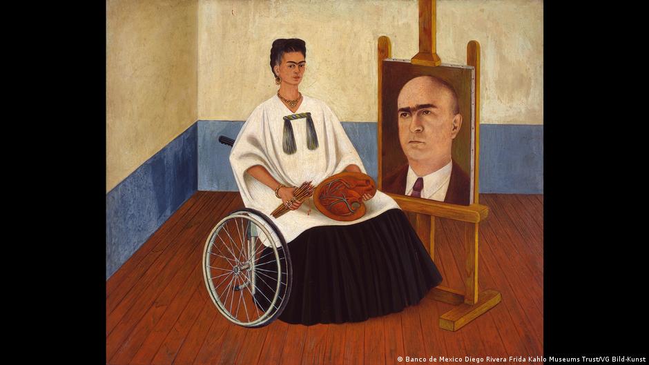 Painting of Frida Kahlo sitting on a wheelchair with paintbrushes and a palette on her lap and there's an easel with a portrait of a man facing her