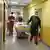 Enfermeiros de máscara empurram cama em corredor de hospital