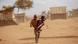 A child carrying a toddler along a dusty road in Madagascar A child carrying a toddler along a dusty road in Madagascar