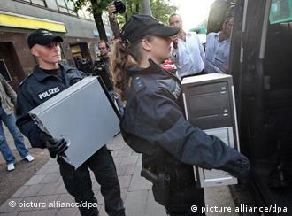 Polizisten tragen beschlagnahmte Computer weg (Foto:dpa)