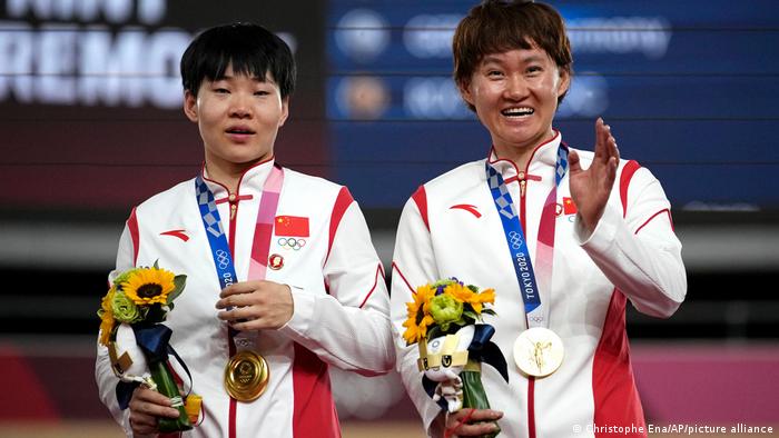 Shanju Bao and Tianshi Zhong celebrate their gold medals during a medal ceremony for the track cycling women's team sprint finals in Tokyo