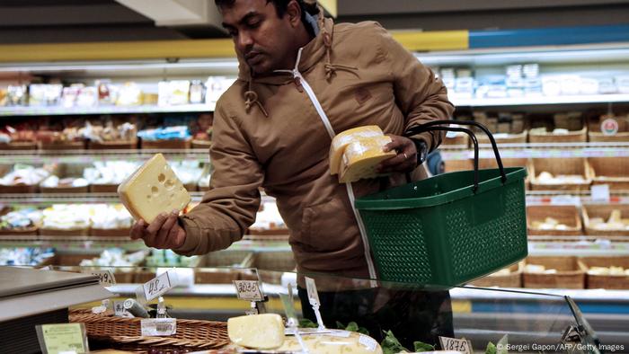 Hombre escogiendo un queso en un supermercado. 