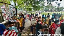 People queue up to get themselves inoculated with the Sinopharm Covid-19 coronavirus vaccine during a mass vaccination camp at Kholamora in Keraniganj district on August 7, 2021. (Photo by Munir Uz zaman / AFP) (Photo by MUNIR UZ ZAMAN/AFP via Getty Images)