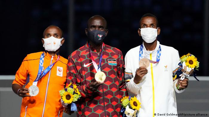 Kenyan gold medalist Eliud Kipchoge stands with Dutch silver medalist Abdi Nageeye and Belgian bronze medalist Bashir Abdi during the men's marathon victory ceremony at the 2020 Summer Olympics in Tokyo, Japan