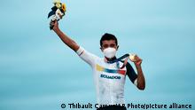 Richard Carapaz of Ecuador reacts on the podium with his gold medal during a medal ceremony, after winning the men's cycling road race at the 2020 Summer Olympics, Saturday, July 24, 2021, in Oyama, Japan. (AP Photo/Thibault Camus)