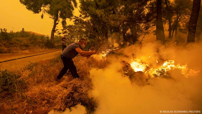 Ein Mann löscht mit einem Ast einen Waldbrand im Dorf Pefki auf der Insel Euböa, Griechenland, 8. August 2021