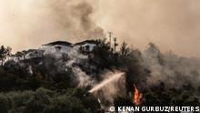 Firefighters spray water to extinguish a fire approaching to a settlement near Cokertme village in Bodrum region, Turkey, August 3, 2021. REUTERS/Kenan Gurbuz