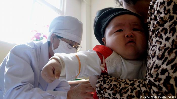 Un médico chino vacuna contra la tuberculosis a un niño.