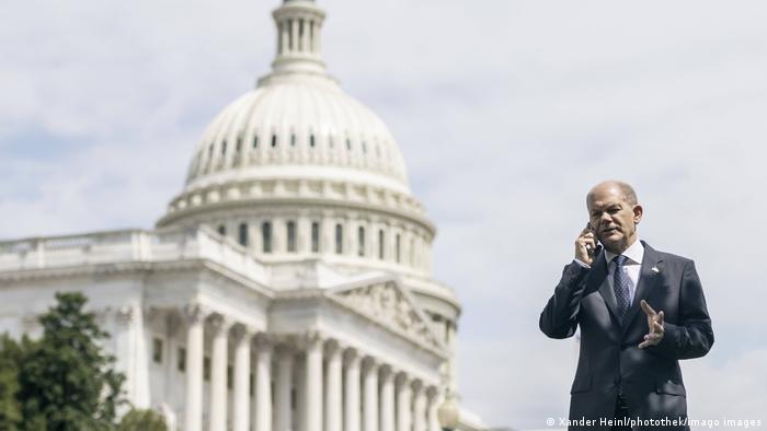 Олаф Шольц говорит по телефону на фоне Белого дома в Вашингтоне