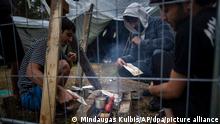 06.08.2021, Litauen, Rudninkai: Migranten bereiten in einem neu errichteten Flüchtlingslager auf dem Truppenübungsplatz Rudninkai Essen zu. Die belarussische Grenzschutzbehörde erklärte am 06.08., sie habe die Kontrollen entlang der Grenze zu Litauen verschärft, um zu verhindern, dass litauische Behörden Migranten nach Belarus zurückschicken. Foto: Mindaugas Kulbis/AP/dpa +++ dpa-Bildfunk +++
