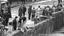 Unter der Aufsicht von bewaffneten Volkspolizisten errichtet eine Ostberliner Maurerkolonne am an der sowjetisch-amerikanischen Sektorengenze am Potsdamer Platz eine Mauer. (zu TV-Dokumentation: Die jüngsten Opfer der Mauer waren noch Kinder) +++ dpa-Bildfunk +++