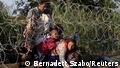 Syrian migrants cross under a fence as they enter Hungary at the border with Serbia, near Roszke, August 27, 2015. Hungary made plans on Wednesday to reinforce its southern border with helicopters, mounted police and dogs, and was also considering using the army as record numbers of migrants, many of them Syrian refugees, passed through coils of razor-wire into Europe. REUTERS/Bernadett Szabo TPX IMAGES OF THE DAY