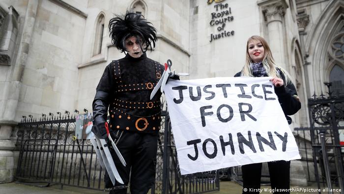 Two people holding a banner that reads Justice for Johnny 