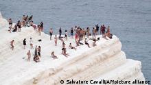 People find comfort in sea breeze at the Scala dei Turchi (Stair of the Turks), a rocky cliff on the coast of Realmonte, near Porto Empedocle, southern Sicily, Italy, Wednesday, Aug. 11, 2021. The ongoing heatwave will last up until the weekend with temperatures expected to reach well over 40 degrees Celsius in many parts of Italy. (AP Photo/Salvatore Cavalli)