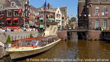 Image of a typical sightseeing boat in a water channel in the inner city of Amsterdam, Holland.