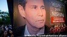 Women stand beside a picture of late prosecutor Alberto Nisman during the one-year anniversary of his death in Buenos Aires, Argentina, Monday, Jan. 18, 2016. Jewish rights groups have organized acts in several Argentine cities. Nisman was found dead in the bathroom of his Buenos Aires apartment on Jan. 18, 2015 with a bullet to his head hours before he was to detail to Congress his accusations that former President Cristina Fernandez and top administration officials orchestrated a secret deal with Iran to shield officials allegedly responsible for the the 1994 bombing of a Jewish community center that killed 85 people. (AP Photo/Natacha Pisarenko)