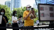 People use their mobile phones to scan a QR health code as a preventive measure against the Covid-19 coronavirus at the entrance of a business district in Beijing on August 10, 2021. (Photo by WANG Zhao / AFP)