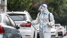 A firefighter wearing protective gear against the spread of Covid-19 coronavirus sprays disinfectant at a residental area in Yangzhou, in China's eastern Jiangsu province on August 11, 2021. (Photo by STR / AFP) / China OUT