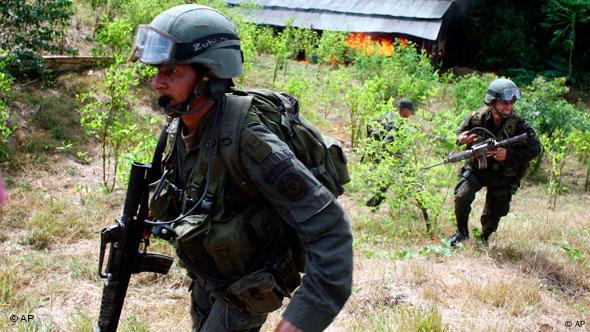 Anti-drug policemen leave a coca field after torching a laboratory to manufacture cocaine in San Miguel, on Colombia's southern border with Ecuador