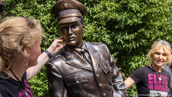 Angela Storm and Meike Berger stand next to a bronze statue of Elvis in Bad Nauheim, Germany