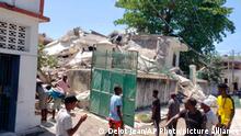 People stand outside the residence of the Catholic bishop after it was damaged by an earthquake in Les Cayes, Haiti, Saturday, Aug. 14, 2021. (AP Photo/Delot Jean)