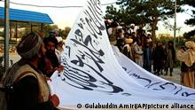 Taliban-Kämpfer hissen ihre Flagge vor dem Haus des Gouverneurs der Provinz Gasni. +++ dpa-Bildfunk +++