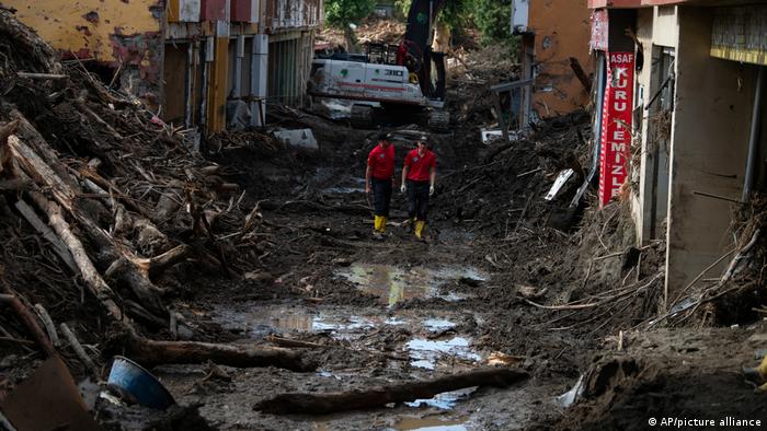 Rescue workers walk along a muddy street following flooding in Bozkurt, Turkey