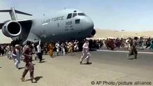 Hundreds of people run alongside a U.S. Air Force C-17 transport plane as it moves down a runway of the international airport, in Kabul, Afghanistan, Monday, Aug.16. 2021. Thousands of Afghans have rushed onto the tarmac at the airport, some so desperate to escape the Taliban capture of their country that they held onto the American military jet as it took off and plunged to death. (Verified UGC via AP)