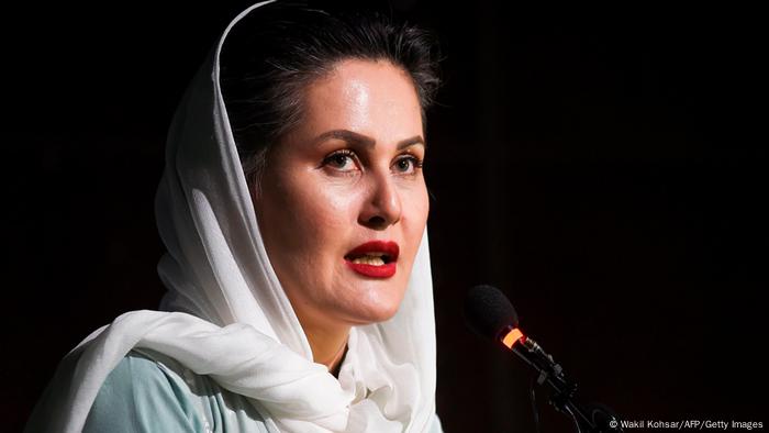 Sahraa Karimi in hijab and wearing red lipstick, speaking in front of a microphone.