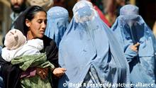 Mit einer verschleierten Freundin unterhält sich eine junge Kabulerin am 28.3.2002 auf einem Markt der afghanischen Hauptstadt. Allerdings machen auch nach dem Sturz des Taliban-Regimes erst wenige Frauen von ihrer neuen Freiheit Gebrauch, sich unverschleiert in der Öffentlichkeit zu bewegen.