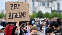 A participant holds up a placard reading 'Help Afghans' during a demonstration near the Chancellery in Berlin on August 17, 2021, to demand the safe passage and airlift out of Afghanistan, where people try flee the country after the Taliban swept back to power. (Photo by John MACDOUGALL / AFP) (Photo by JOHN MACDOUGALL/AFP via Getty Images)