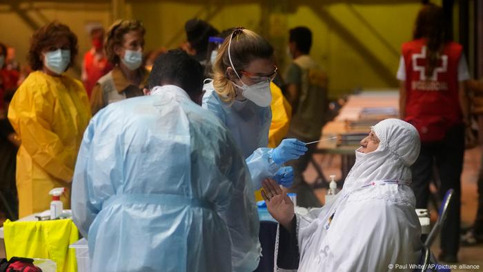 Klinisches Personal mit Schutzkleidung macht einen Test bei einer afghanischen Frau Klinisches Personal mit Schutzkleidung macht einen Test bei einer afghanischen Frau