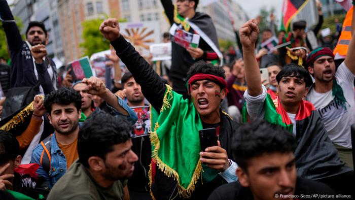 Homens levantam os punhos e gritam em manifestação de rua